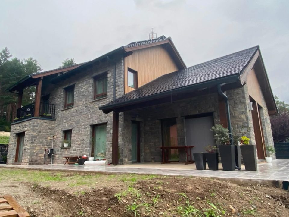 Vivienda terminada de piedra y madera con porche cubierto